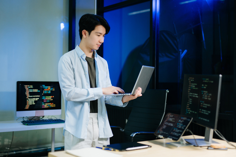 Young male programmer working with tablet and screen displaying