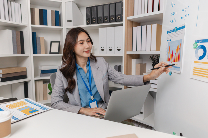 Confident businesswoman working in a modern office, managing reports and communicating by phone while reviewing data to make decisions and improve team performance.